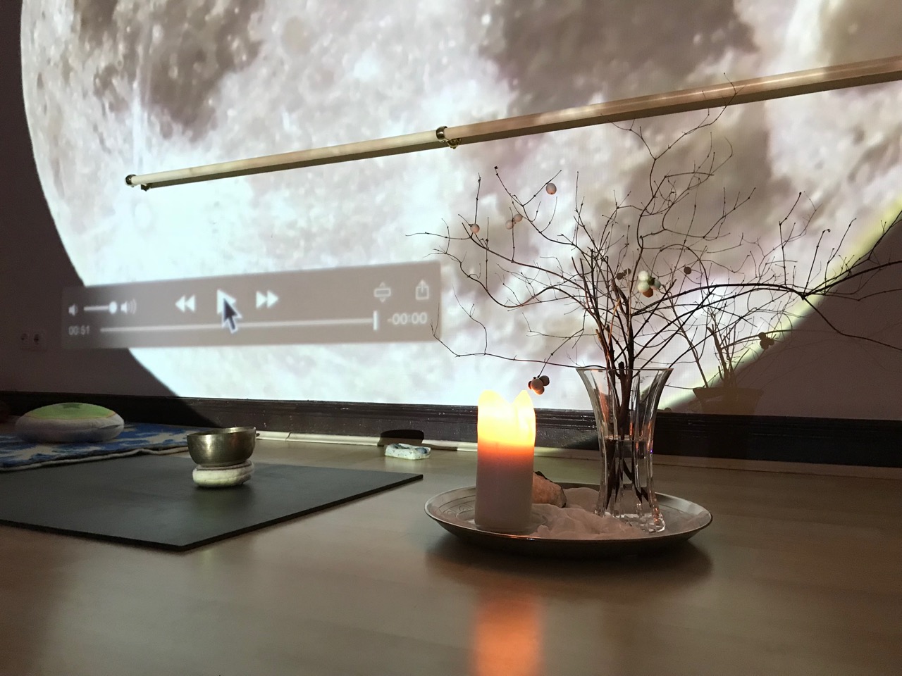 Yoga Vollmond: Ein Tabeltt mit einer Vase voll Zweigen und eine Kerze vor einem Mond-Foto