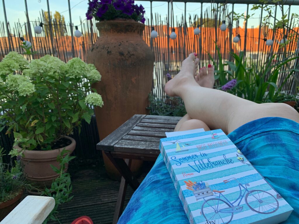 Buch "Sommer in Villefranche" auf den Knien