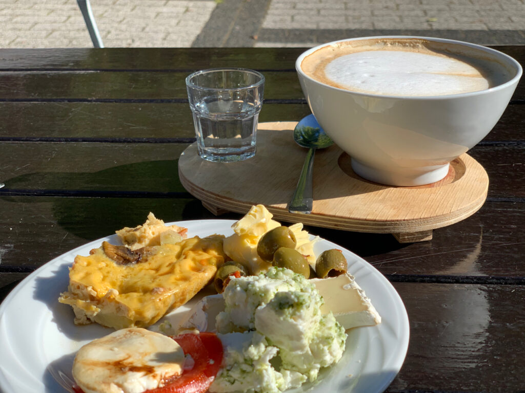 Frühstück im Seitenblick: Milchkaffee mit einem bunten Teller
