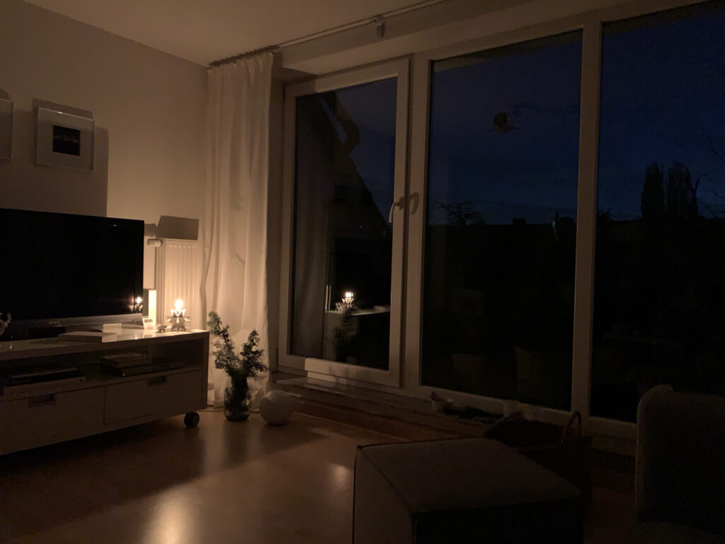 Auf den Sonnenaufgang warten: Dunkles Wohnimmer, nur von einer Kerze beleuchtet