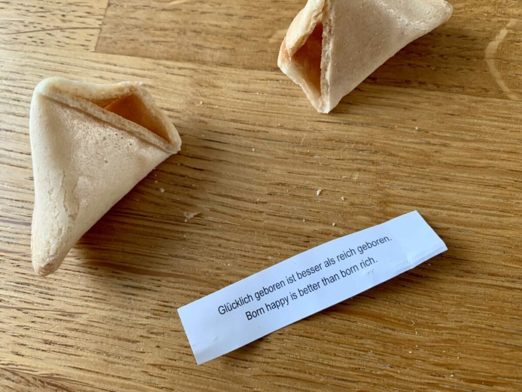 Aufgebrochener Glückskeks mit Textstreifen: Glücklich geboren ist besser als reich geboren