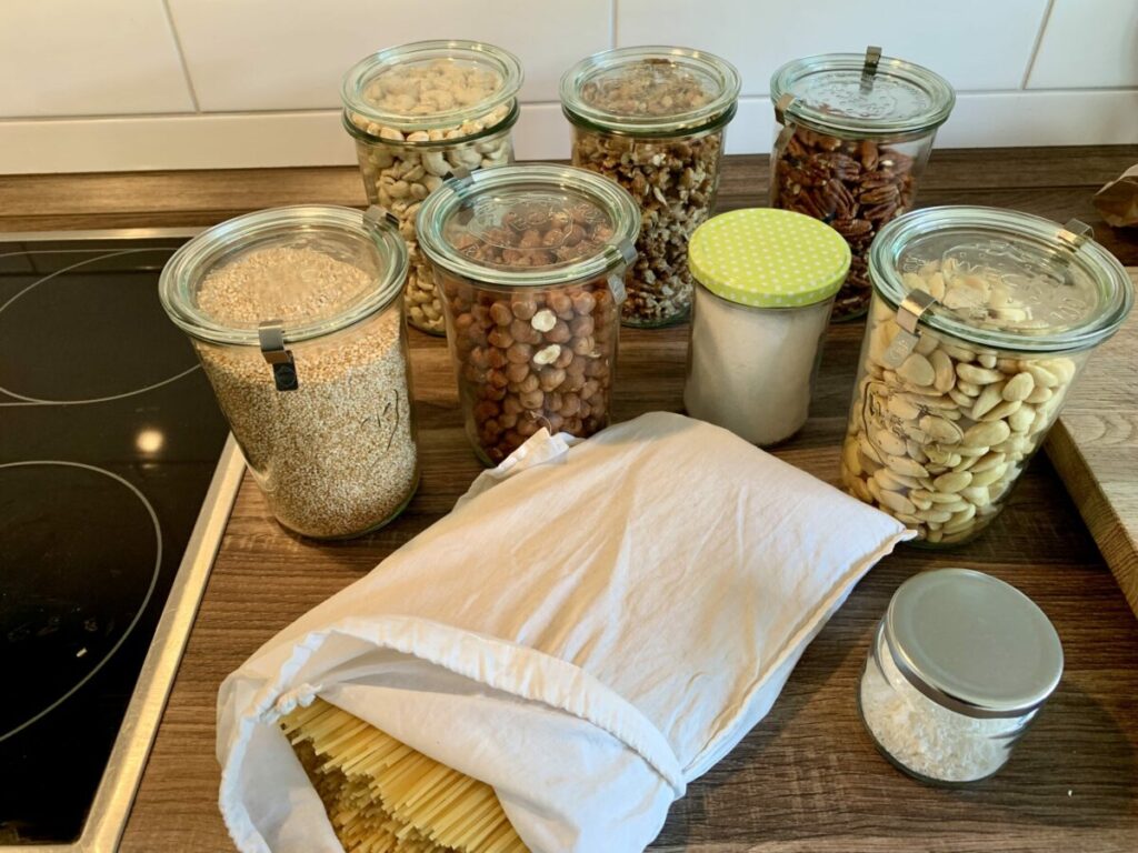 Einkauf aus dem Unverpacktladen: Weckgläser mit verschiedenen Nüssen, gepufftes Amarath, Kokosflocken, Salz im Glas und ein Baumwollbeutel mit Spaghetti