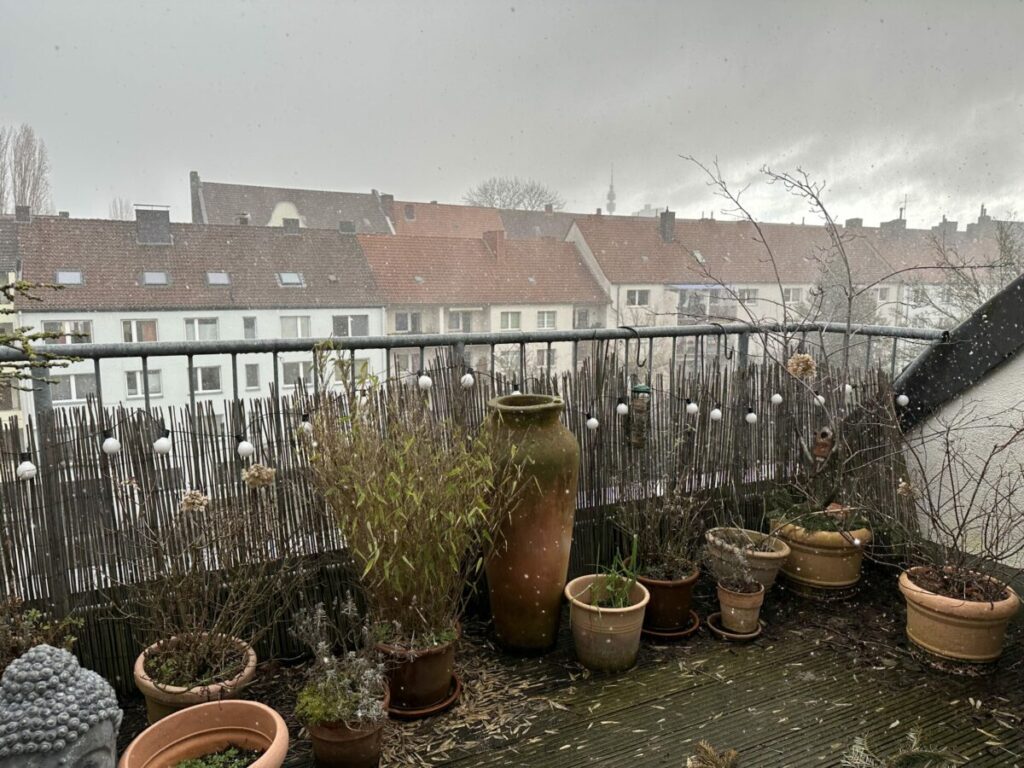 Ausblick auf die winterliche Dachterrasse: Der Himmel dunkel und es hagelt und schneit.