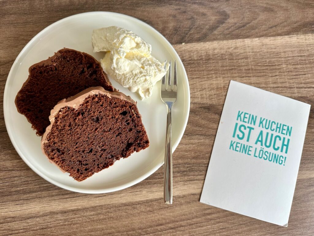 2 Stücke Schoko Rote Bete Kuchen auf einem teller, dazu ein Klecks Sahne. Daneben liegt eine Karte auf der steht "Kein Kuchen ist auch keine Lösung".
