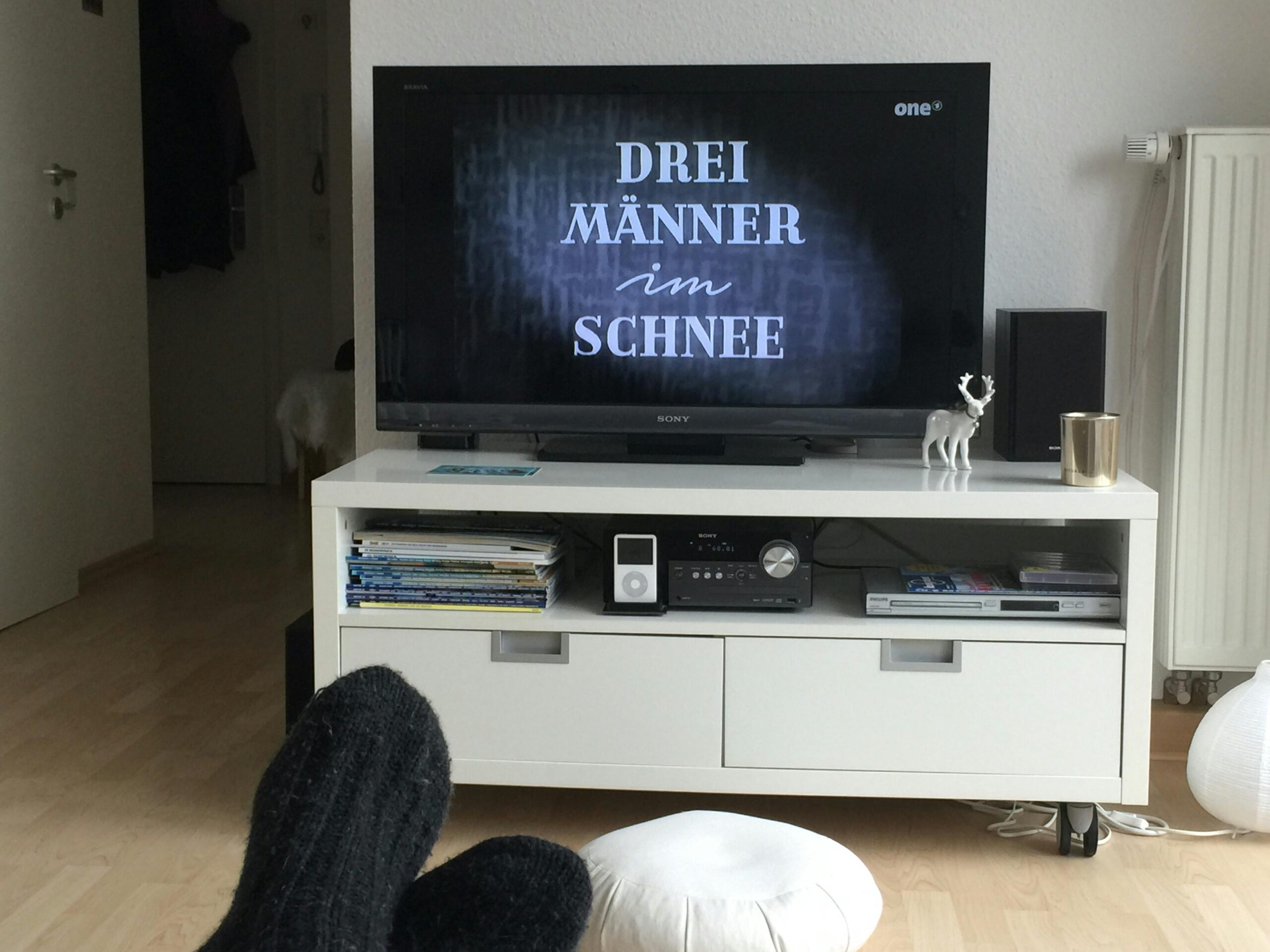 Fernsehbildschirm mit dem Titelbild von "Drei Männer im Schnee".