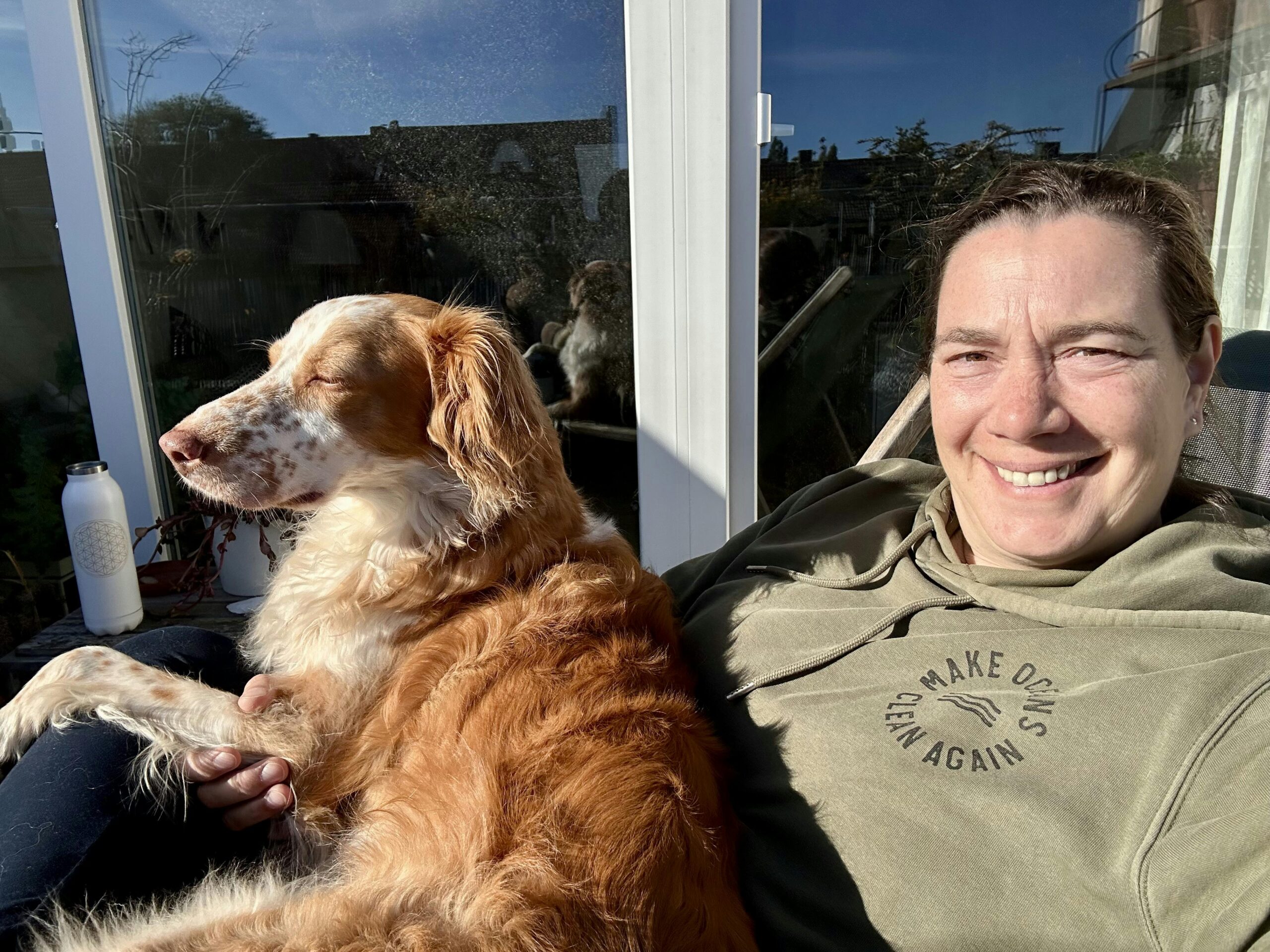 Frau mit Hund auf dem Schoss sitzen in der Sonne