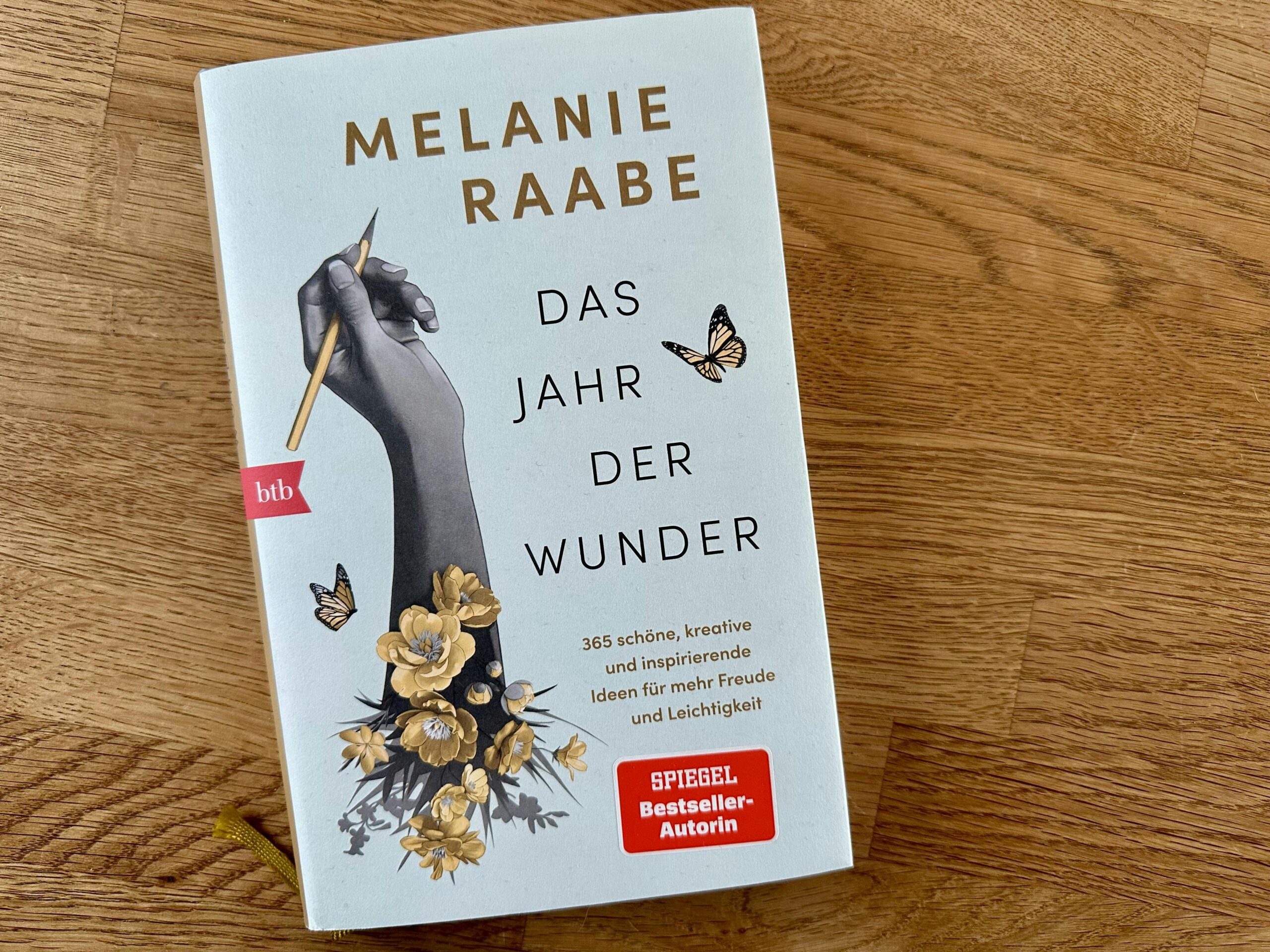 Buch "Das Jahr der Wunder" von Melanie Raabe auf einem Holztisch