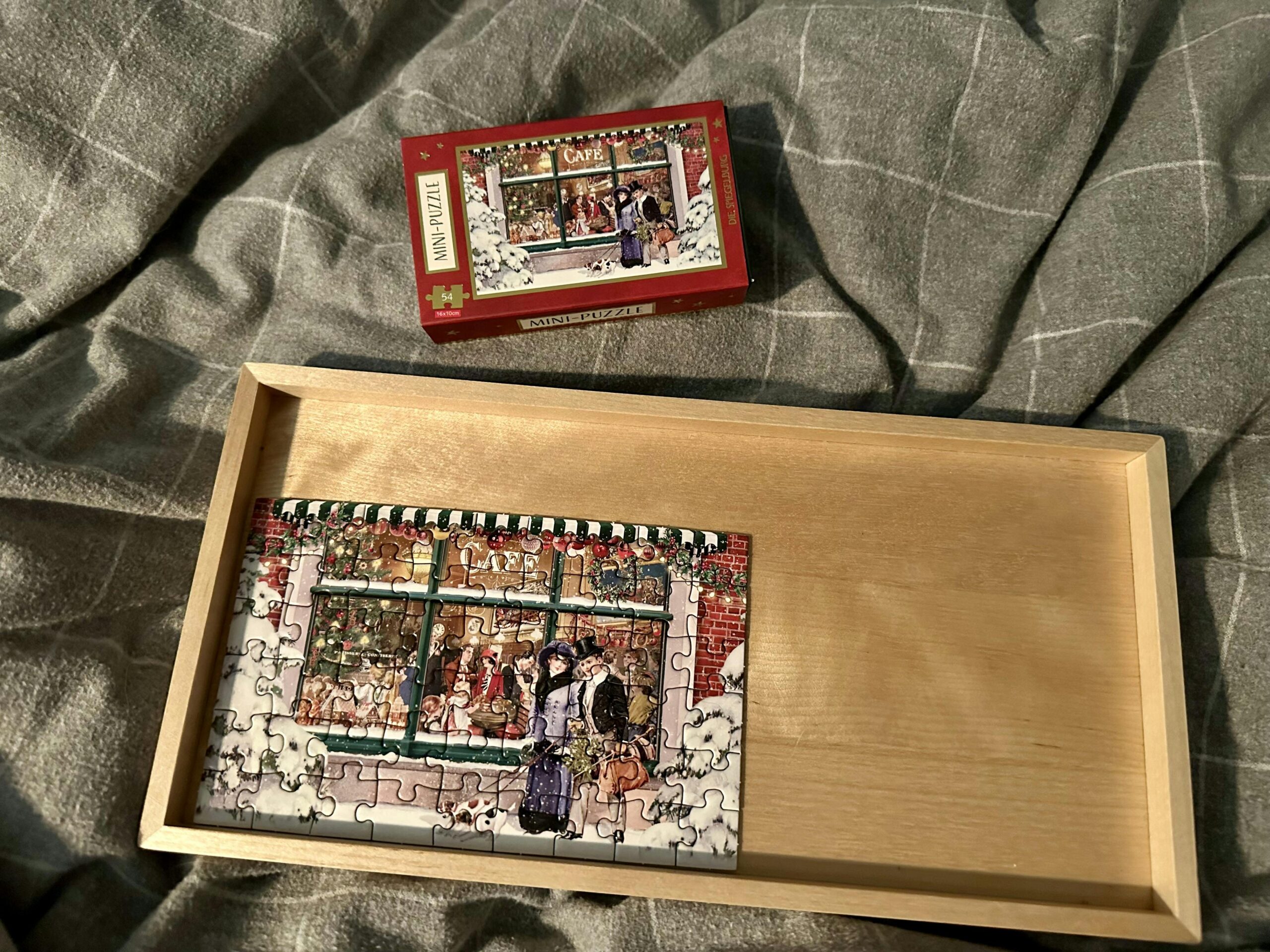 Kleines Holztablett mit einem Mini-Puzzle mit weihnachtlichem Motiv. Daneben der Puzzle-Karton.