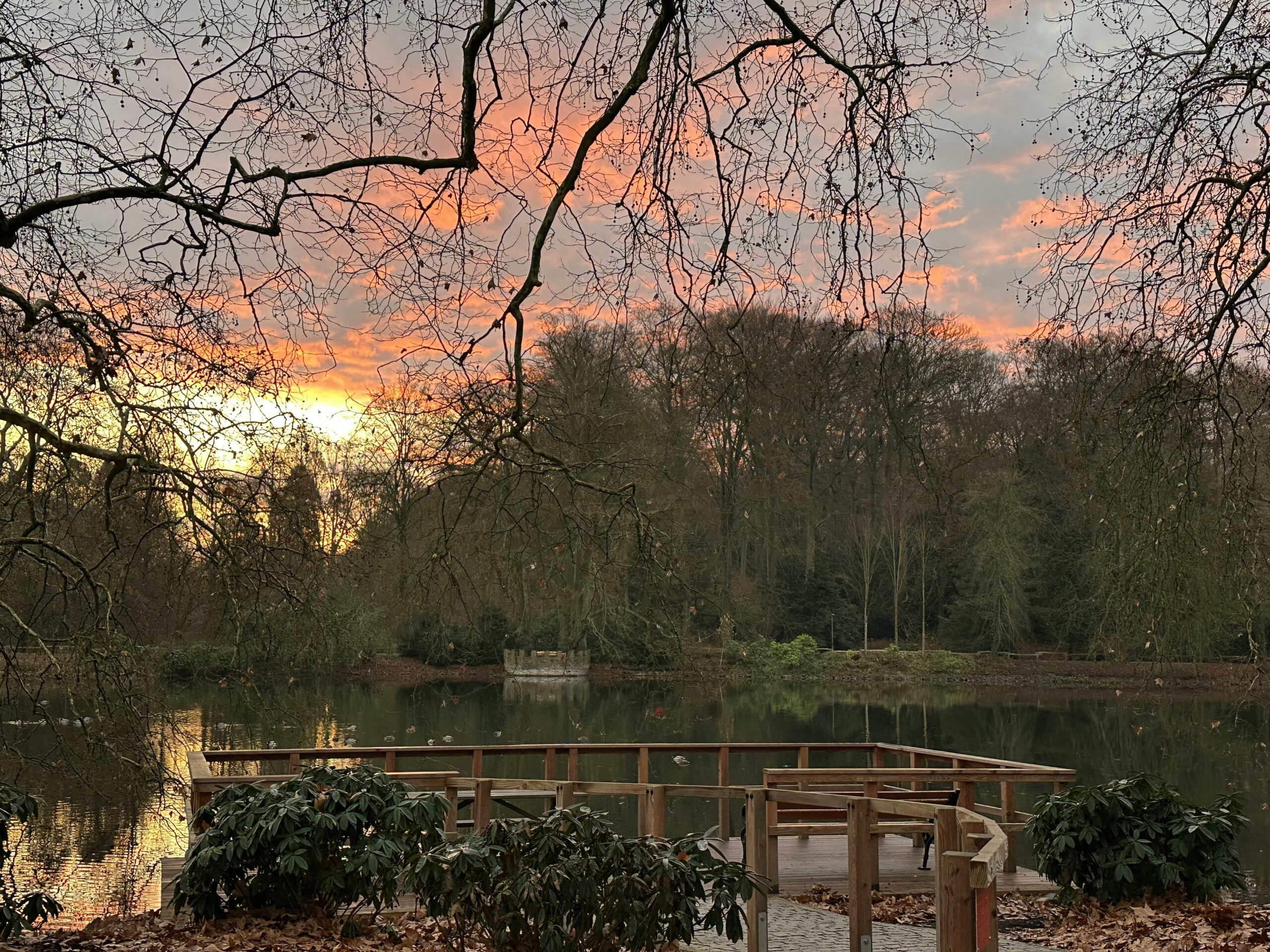 Blick auf einen See im Winter mit orange-farbenem Himmel