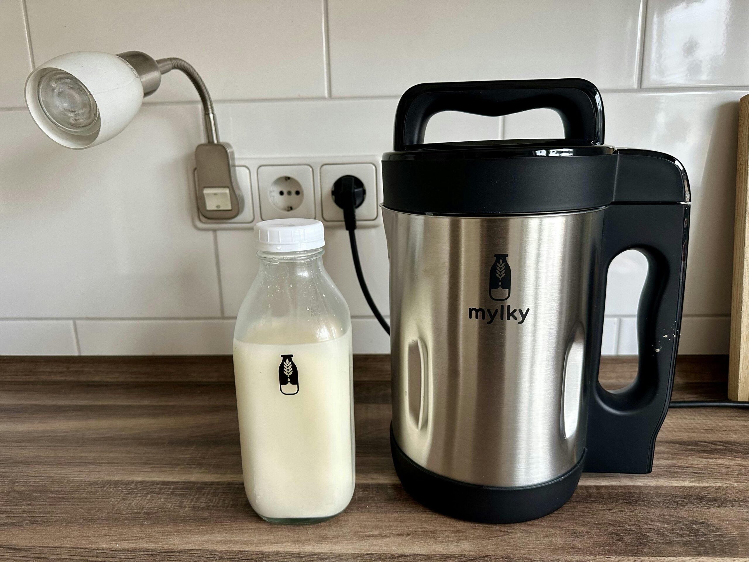 Mylky-Pflanzenmilchmaschine neben einer Flasche mit Pflanzenmilch.
